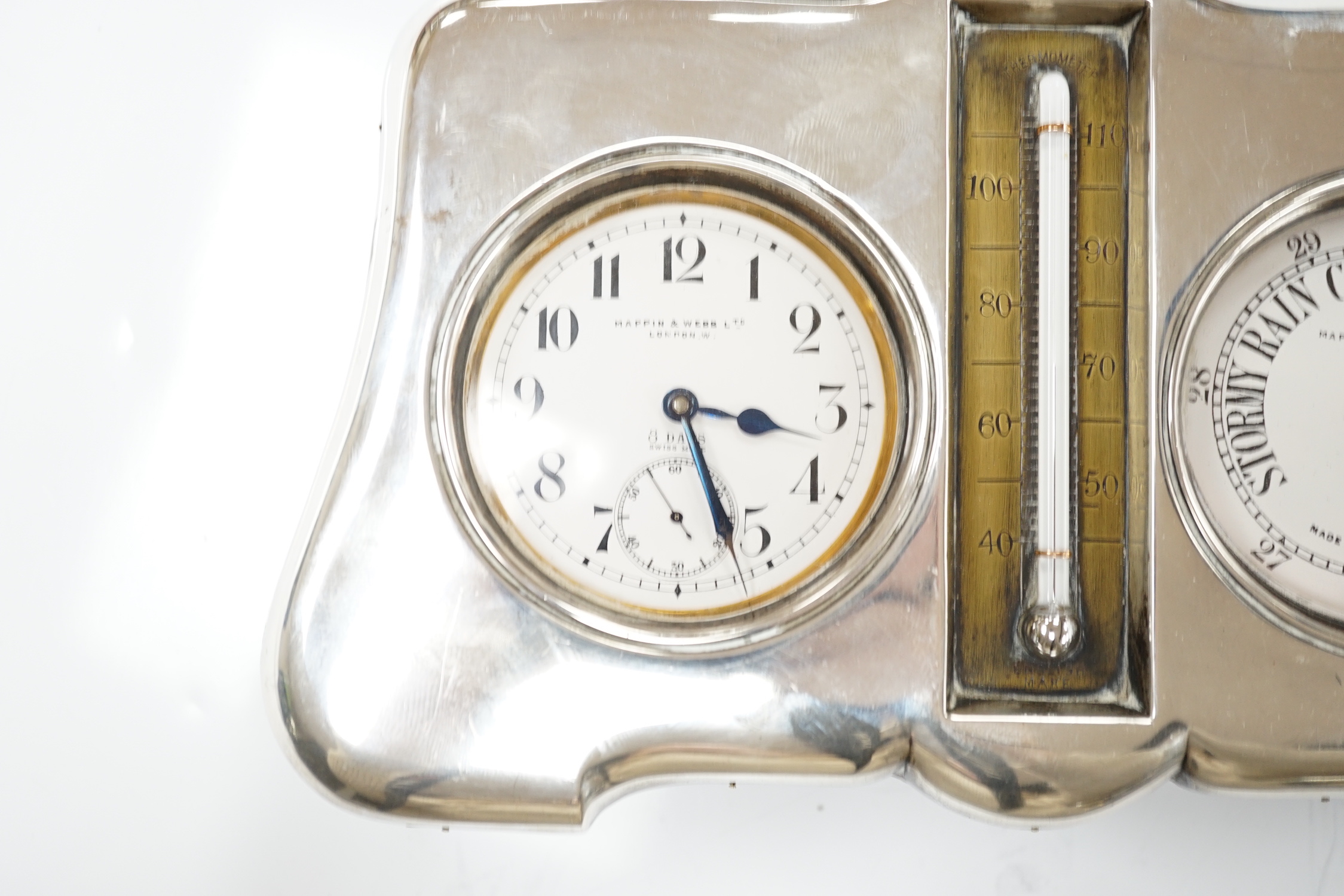 An Edwardian silver mounted leather clock/barometer desk stand, containing a pocket watch, retailed by Mappin & Webb, a similar barometer and a central thermometer, Henry Matthews, Birmingham, 1905, width 21.2cm.
